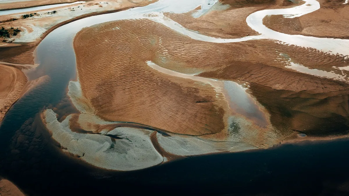 Aerial shot of winding river bends on sandy terrain in Terengganu, Malaysia, showcasing natural beauty and eco